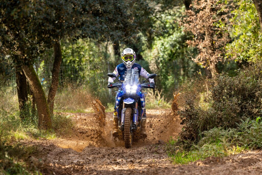 Piloto con Yamaha Ténéré 700 atravesando un tramo de barro en el bosque