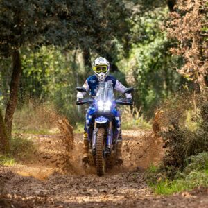 Piloto con Yamaha Ténéré 700 atravesando un tramo de barro en el bosque